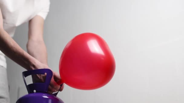 Young Caucasian Unrecognizable Man White Shirt Inflates Red Heart Balloon — Stockvideo