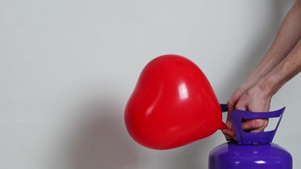 Young Caucasian Unrecognizable Man White Shirt Inflates Balloon Red Heart — Stockvideo