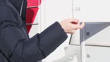 Mavi ceketli genç beyaz bir adam bir posta kutusunu açar ve ondan bir paket kutusu çıkarır, yakın çekim. Paket alma kavramı, modern bir yaşam tarzı..