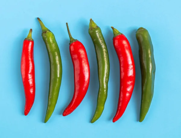Sześć Ostrych Papryczek Chili Kolorze Czerwonym Zielonym Leży Rzędzie Jasnoniebieskim — Zdjęcie stockowe