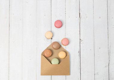 Beyaz ahşap bir masanın üzerinde duran bir zarfın renkli kurabiyelerinden düşmek. Kenarlarında fotokopi alanı, yakın plan yatma. Tatlı tatlı konsepti..