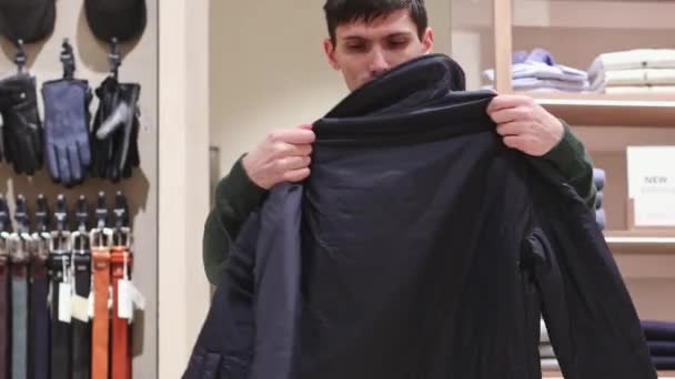 一位年轻的白人男子在一家服装店里检查并折叠一件新夹克 近距离侧视 离线购物概念 现代生活方式 — 图库视频影像