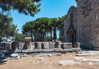 Yunanistan 'ın Rodos adasındaki Filerimos Dağı' nda Malta haçı bulunan Meryem Ana tapınağının yanındaki antik Athena ve Zeus tapınağının yıkık mimari taşlarının güzel manzarası. Tarihi yapı kavramı.