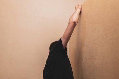 Arka taraftaki siyah tişörtlü, elleri yatak odasındaki dolaptan kontrplaklı beyaz tenli genç adam, yakın plan saha derinliğinde. Mobilya montaj konsepti..