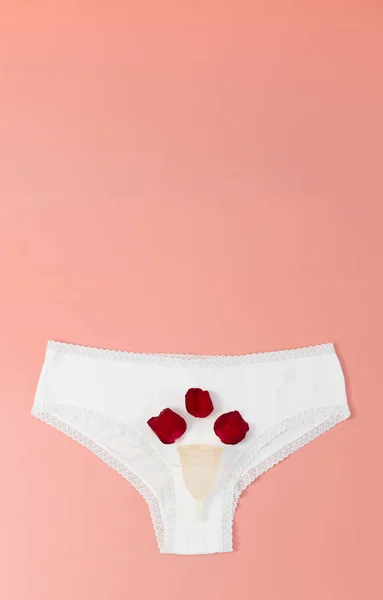Jedna Biała Damska Majteczka Silikonowym Kubkiem Menstruacyjnym Trzema Czerwonymi Płatkami — Zdjęcie stockowe