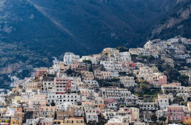 İtalya 'nın Positano şehrinde yaz güneşli bir günde yeşil ağaçlarla kaplı dağlardaki renkli konut manzaralı evler..