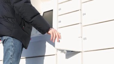 Kot pantolonlu ve ceketli genç bir adam aşağıdan yakın çekim görüntüsü olan beyaz bir posta kutusundan bir paket alıyor. Paket alma kavramı.