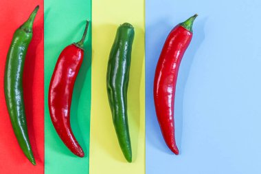 Dört baharatlı yeşil ve kırmızı kırmızı biber renkli bir arka planda duruyor, fotokopi alanı küçük, düz yakın plan. Cinco de Mayo konsepti, minimalizm, boşluk.