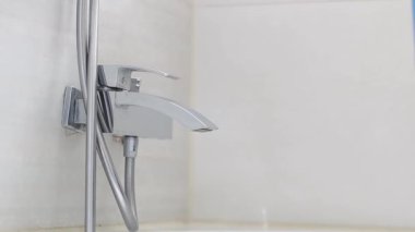 Beyaz elbiseli, sarı eldivenli genç bir kadının elleri şeffaf bir şişeyi mavi sıvıyla tutuyor ve banyodaki kirli bir musluğa sıkıyor, yavaş çekimde yan görüntüyü kapatıyor. Tuvalet konseptini temizlemek..
