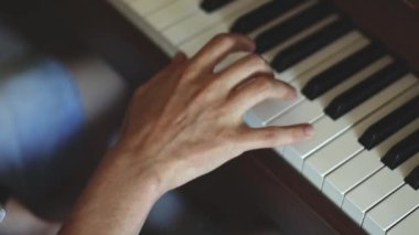 Piyano çalarken tuşları parmaklayan beyaz bir adamın eli, yavaş çekim ve alan derinliği ile yan plan. Müzik konsepti, müzik dersi, müzik hobisi, müzik eğitimi..
