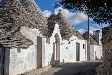 Güneşli bir günde Alberobello kasabasında ünlü Trulli evleri olan dar bir caddenin güzel manzarası, puglia, italyan manzara,.