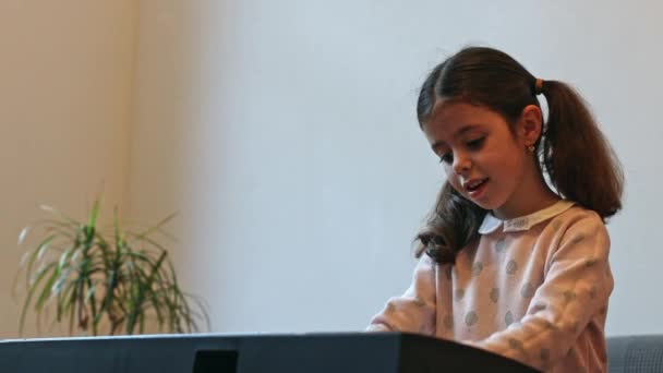Όμορφη Μικρή Καυκάσια Μελαχρινή Κοπέλα Δύο Αλογοουρές Παίζει Ηλεκτρικό Πιάνο — Αρχείο Βίντεο