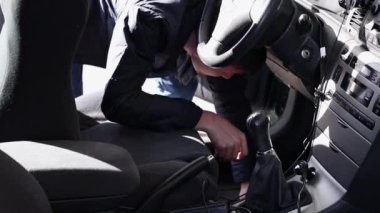 Kafkasyalı bir genç, güneşli bir bahar gününde açık bir araba yıkama yerinde arabasının iç tarafına lastik bir paspas seriyor..