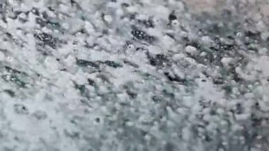 Umumi bir oto yıkamada arabanın ön camından akan sabunlu su..