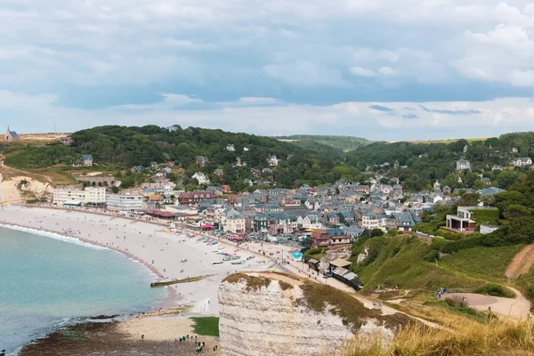 stock image A beautiful view of the village immersed in greenery on the shores of the North Sea in Etretat, Normandy, France with vacationing tourists on a clear spring day, close-up side view from above.