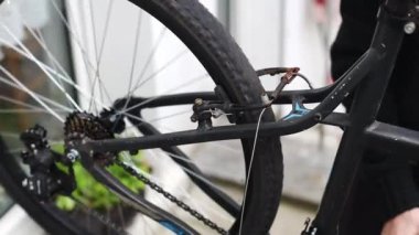 Genç beyaz bir adam evinin arka bahçesinde dikilirken bisikletinin tekerleğini ve arka frenlerini kontrol ederken pedal çeviriyordu. Bisiklet tamir konsepti.