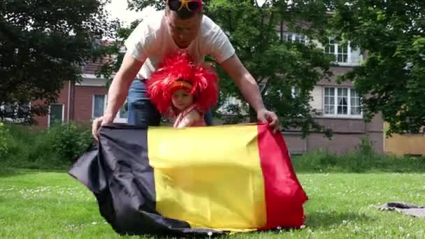 Młody Ojciec Okularach Przeciwsłonecznych Rozwija Belgijską Flagę Dla Córeczki Czerwonej — Wideo stockowe