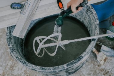 Kafkasyalı genç adam macundan tanınmaz hale geldi. Siyah bir havuzda, duş ağının altında, seçici bir odak noktası olan bir inşaat mikseri var. Ev yenileme konsepti, inşaat işi.