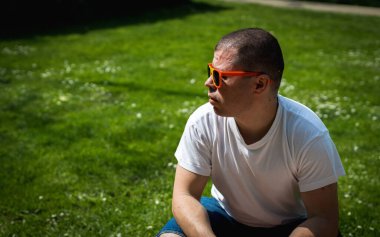 Belçika bayrağı takmış yakışıklı beyaz bir adamın portresi Belçika bayrağını güneşli bir yaz gününde şehir parkında piknikte kutluyor...