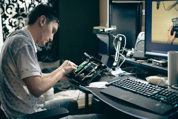 ジョイスティックでモーターコントロールホイールを修理した若い白人男性 接続ワイヤー 部屋のコンピュータデスクでアームチェアに座って クローズアップサイドビュー — ストック写真