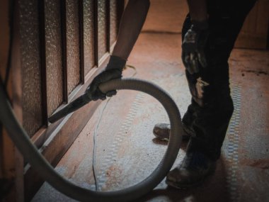 Beyaz tenli genç bir adam evin ana kirli geçidini elektrikli süpürgeyle süpürüyor. Tadilata hazırlanıyor..