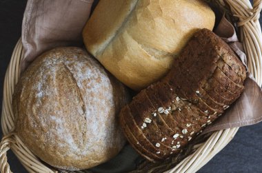 Oval hasır sepetin üç farklı çeşidi ve şekli siyah taş bir masanın üzerinde yatar, düz yakın plan. Ekmek pişirme konsepti.