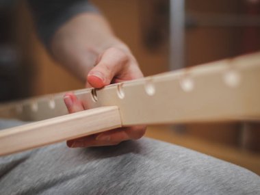 Kafkasyalı bir gencin elleri döşeklerin altında iki ahşap tahtayı birbirine bağlıyor. Odasının zemininde oturuyor, tarlanın derinliği ile yakın plan manzarası var. Paket teslimatı, mobilya montajı, alışveriş konsepti.