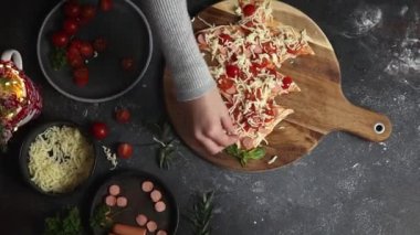 Küçük kız noel ağacına mozzarella peyniri serpiyor. Ev yapımı pizza hamuru. Koyu bir masanın üstünde. Aile eğlencesi ve yemek yapma konsepti.