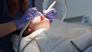 Leylak rengi eldivenli genç bir diş hekiminin elleri, diş eti ve su kullanan bir kızın diş etlerini derin bir şekilde temizler..