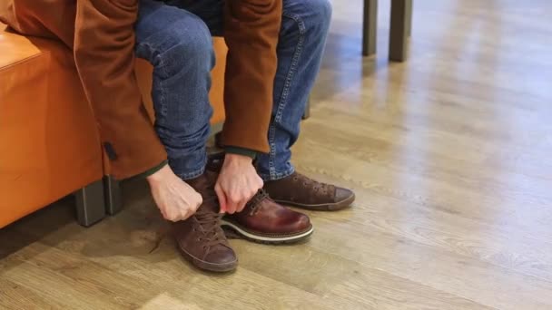 코트를 잘생긴 코카서스 머리는 새로운 신발을 시도하기 오래된 신발을 가게에서 — 비디오