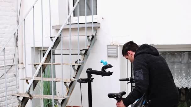 Joven Caucásico Cuelga Una Bicicleta Estante Plástico Negro Para Reparar — Vídeo de stock