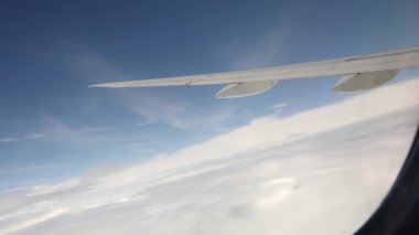 Gökyüzünün güzel panoramik manzarası beyaz bulutlar ve pencereden uçan bir uçağın kanadı ve bir yaz günü pürüzsüz bir dönüş yapıyor, yakın bir yan görüş. Yavaş çekim.