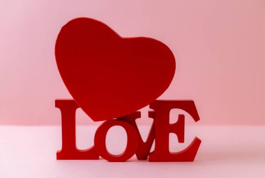 Kırmızı karton kutu ve ahşap sert kelime Aşk pembe bulanık arka planda, yakın planda yatar. Sevgililer Günü konsepti.