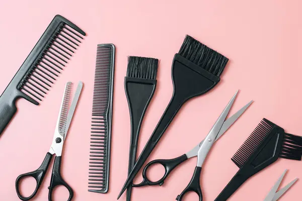 A set of hairdressers tools from scissors,brushes and combs on a pink background,flat lay closeup. The concept of hairdressing, beauty salon, tools.