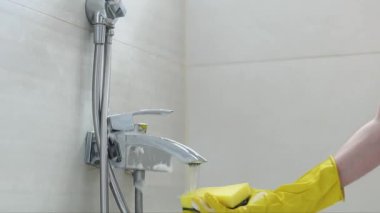 Sarı eldivenli beyaz bir kadının elleri banyoda akan suyun altında deterjanla süngeri duruluyor. Yan görüntüsü yavaş çekimde. Tuvalet konseptini temizlemek..