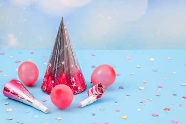 Bir pembe koni doğum günü şapkası, üç şişirilmiş mini balon ve dağınık kağıt konfetili iki ıslık sol arka planda bulanık bokeh ve sağ tarafta kopyalama alanı olan iki ıslık.