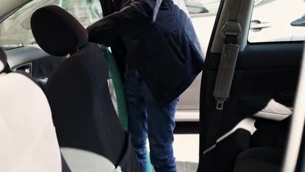在明媚明媚的春日 一个年轻的白种人正在用吸尘器吸空自己车内的乘客座位 — 图库视频影像