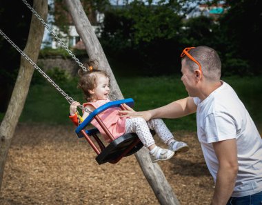 Yakışıklı, genç, beyaz bir adam babası, küçük ve mutlu kızına biniyor. Bir yaz günü parkta salıncakta salıncakta, çocuk parkında..