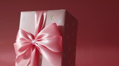 Bir adet hediye kutusu, büyük pembe bir fiyonk ve paketin üzerinde kalpler var. Pembe, alt tarafı yakın plan, sağa doğru dairesel bir dönüş..