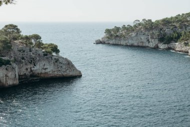 Fransa 'nın Calanques şehrinde bir yaz günü, Akdeniz' de bitki örtüsü olan iki kayalık dağ arasındaki körfezin girişinin güzel manzarası, tarlanın derinliği ile yakın plan manzarası..