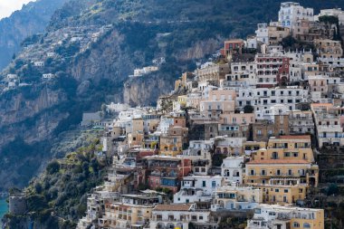 İtalya 'nın Positano şehrinde yaz güneşli bir günde yeşil ağaçlarla kaplı dağlardaki renkli konut manzaralı evler..