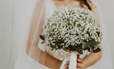 Beyaz elbiseli, duvak takmış, beyaz yaka çiçekli bir düğün buketini elinde tutan tanınmayan beyaz bir gelinin portresi..