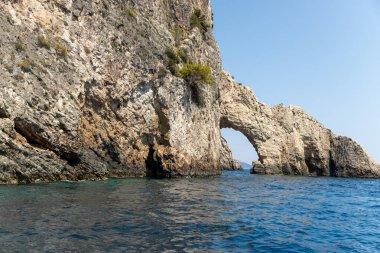 Güneşli bir yaz gününde, açık gökyüzü, zakynthos adasında, mavi denizde küçük kayalık bir kemerin güzel manzarası..