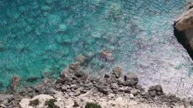 Güneşli bir yaz gününde, kıyıya yakın kayalık bir tabanı olan, temiz ve temiz bir su sıçratan güzel bir atmosfer manzarası, yukarıdan yakın bir manzara. Seyahat zamanı konsepti, doğal arka planlar.
