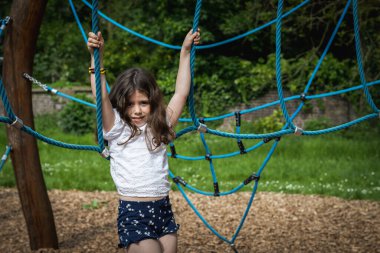 Kafkasyalı güzel bir esmer kızın portresi elleri ile bir yaz günü parkta salıncakta sallanan mavi bir halat, oyun parkında, yakın çekimde..