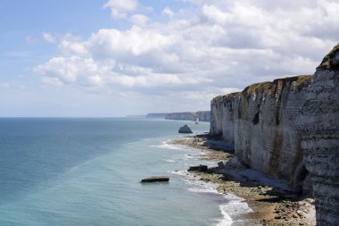 Kuzey Denizi 'nin alçak sularındaki kayalık sahilin güzel manzarası bulutlu bir yaz günü Etretat, Normandiya' da, yan manzara.