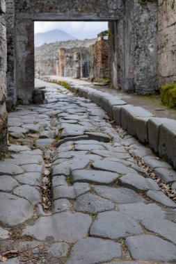 İtalya 'da bulutlu ve bulutlu bir yaz gününde, Pompeii antik kentinde kaldırımlı taş bir merkez caddenin enkazının güzel manzarası..