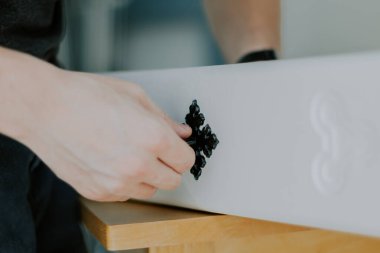 Tanımlanamayan beyaz bir adamın elleri beyaz bir çekmeceye oyulmuş antika bir siyah sapı yerleştirir..