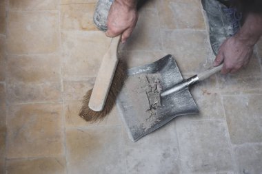 Kirli fayanslı bir zeminden eski bir faraş üzerinde küçük bir çırpıyla inşaat enkazını süpüren tanınmayan genç beyaz bir adam. Pencereleri temizleme ve kurma kavramı