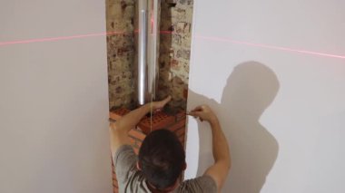 Genç yakışıklı bir adam, beyaz bir müteahhit, şöminenin taze çimento havan tuğlaları arasındaki küçük çatlakları kapatmak için dar bir spatula kullanır.